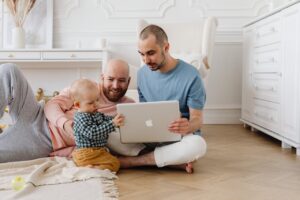 two guys playing with the baby and on a laptop