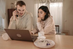 A Man Talking on the Phone while his wife looking at laptop