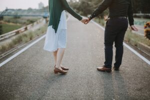 couple holding hand while walking on road
