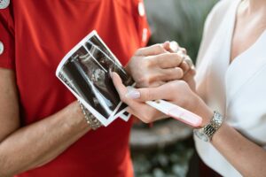 couple holding ultrasound result and pregnancy's test kit