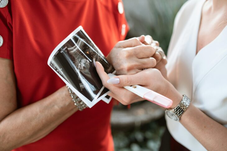 couple holding ultrasound result and pregnancy's test kit